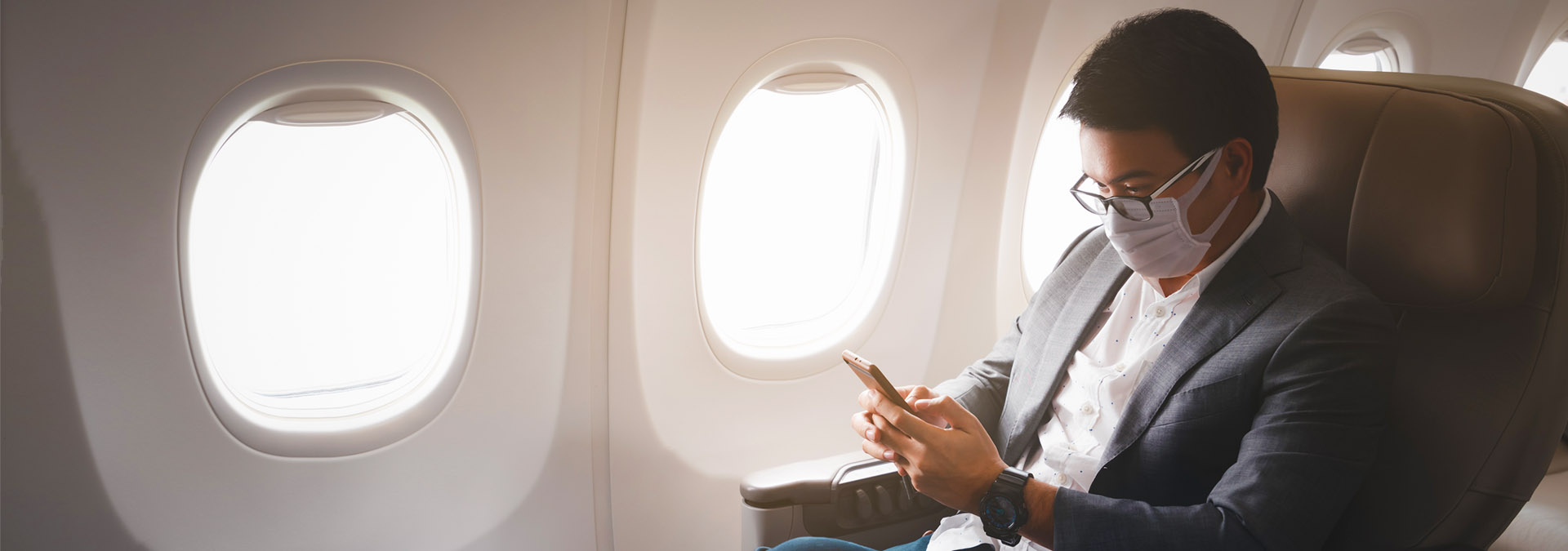 Masked man on a plane with phone